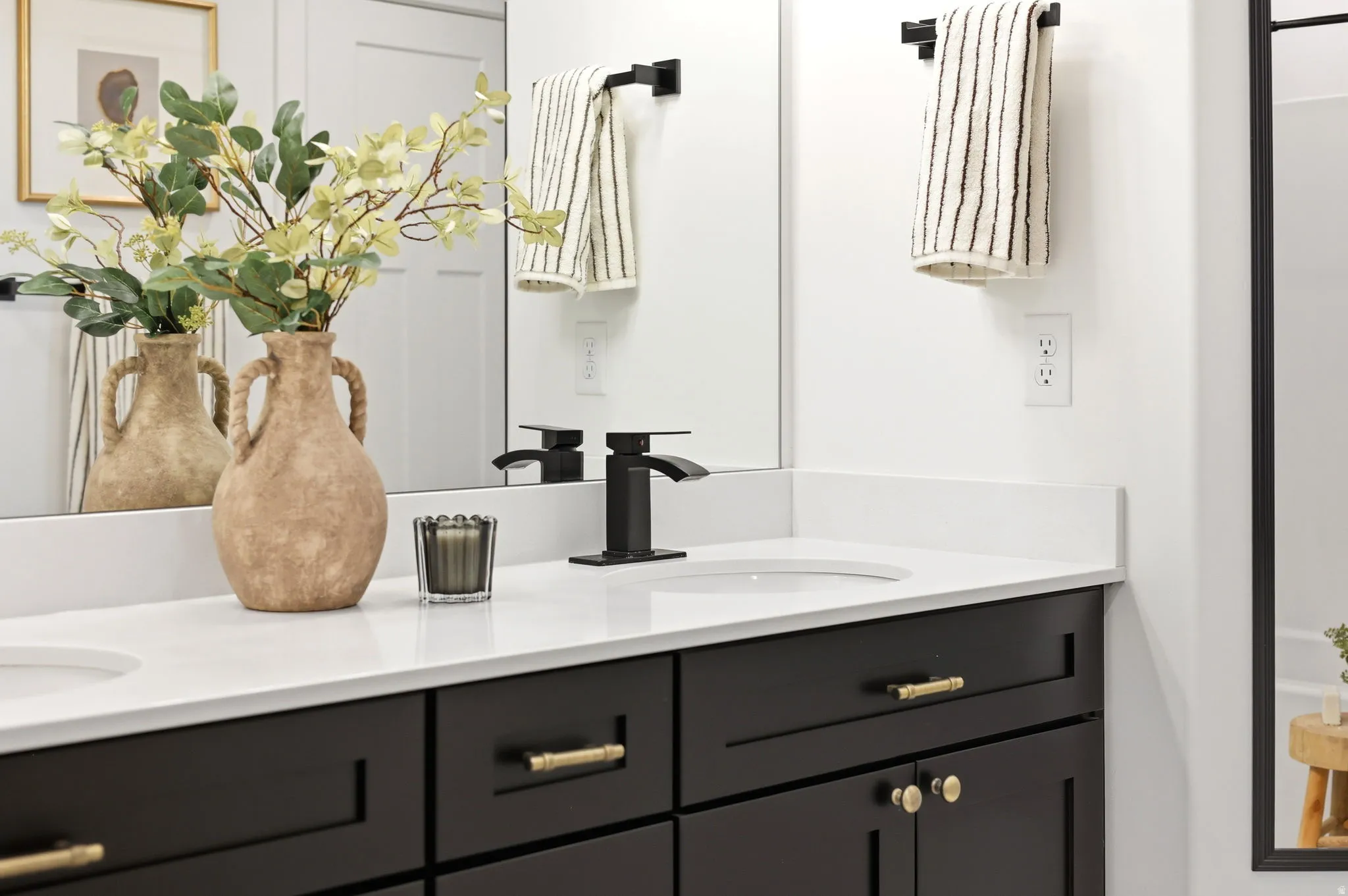 Double vanity featuring black cabinetry, white countertops, dual undermount sinks, and matte black faucets