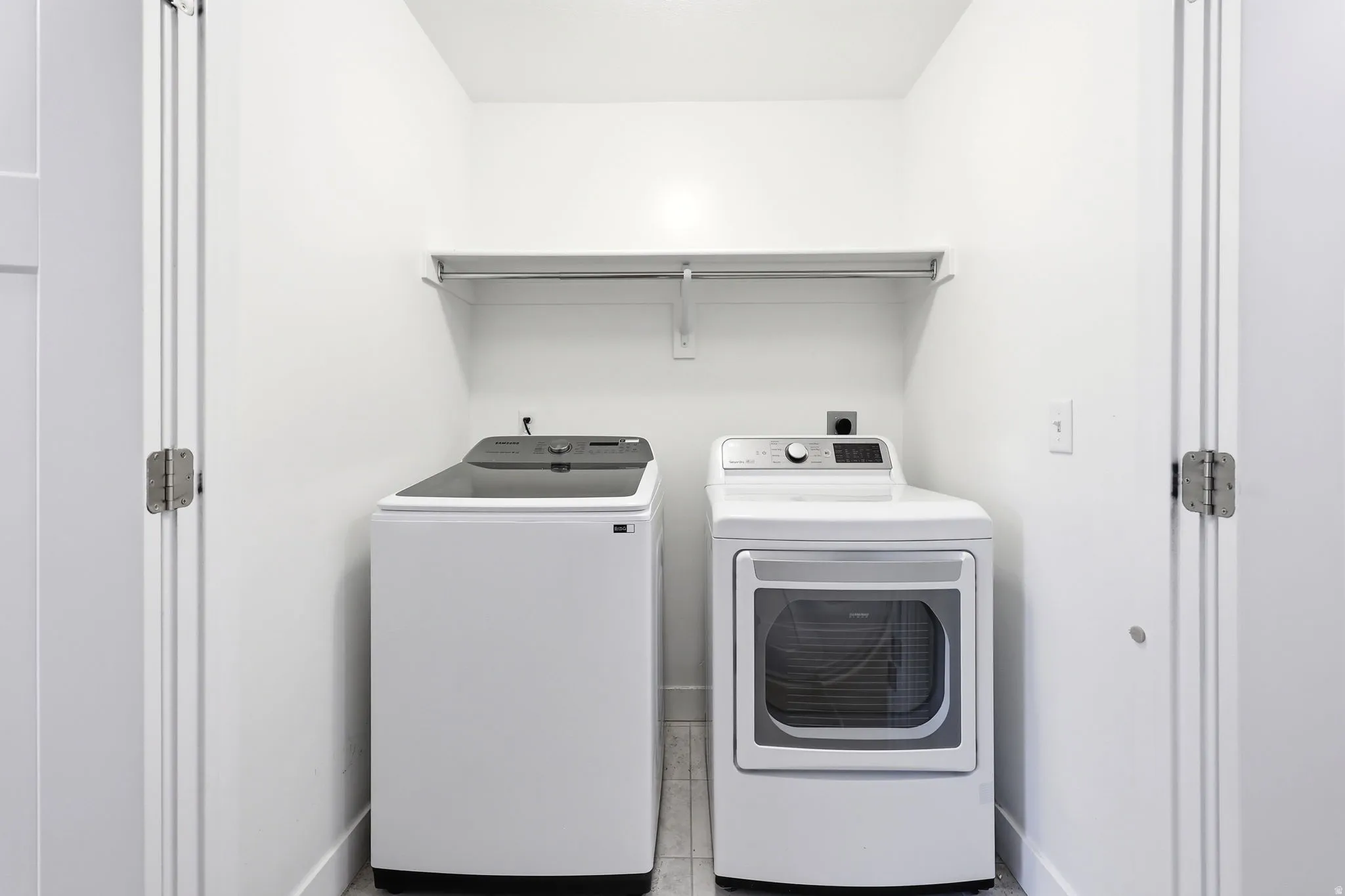 Dedicated laundry area featuring a white top-load washer, a white front-load dryer, and an overhead storage shelf