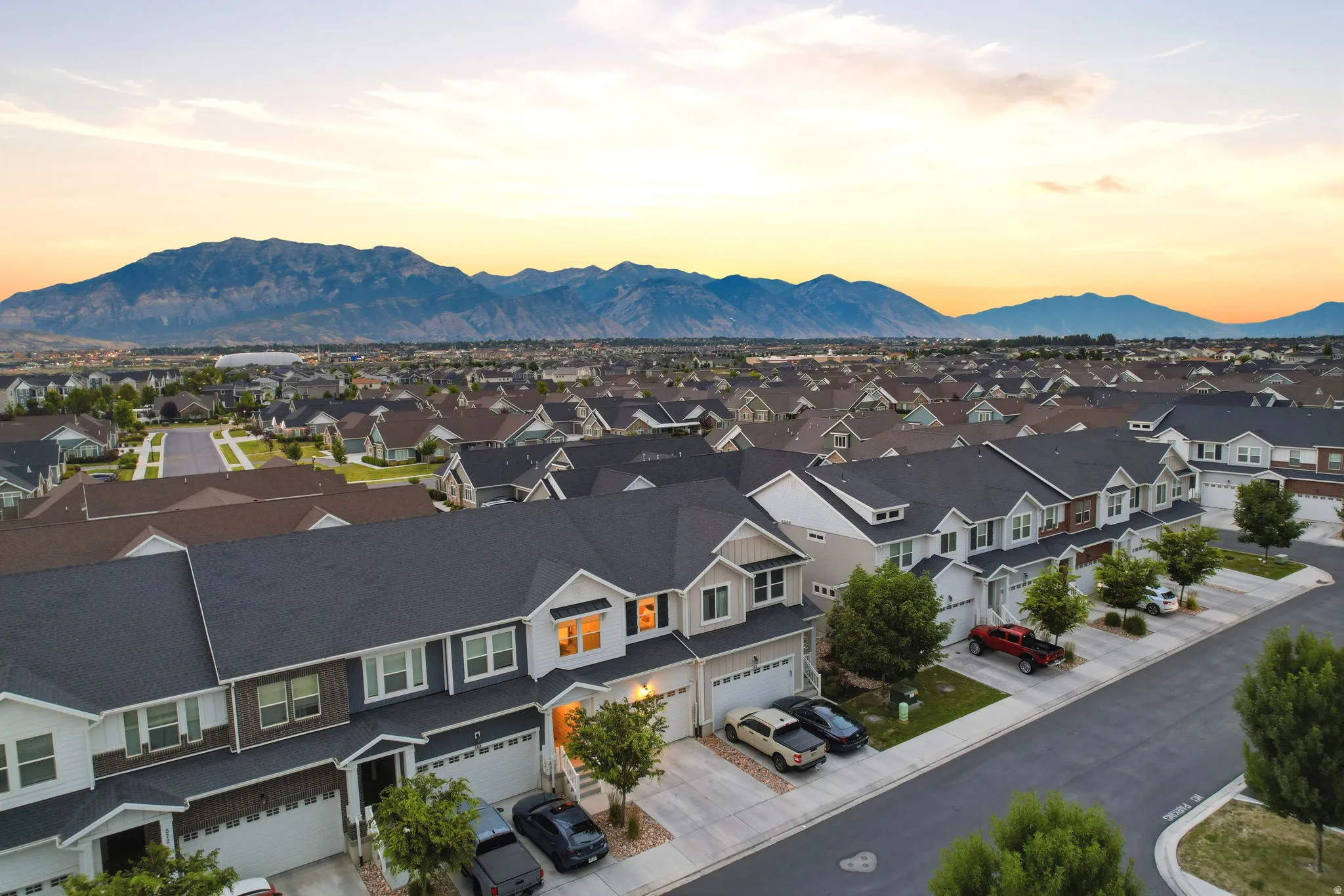 Residential neighborhood featuring a consistent architectural style, paved streets, and a mountainous backdrop