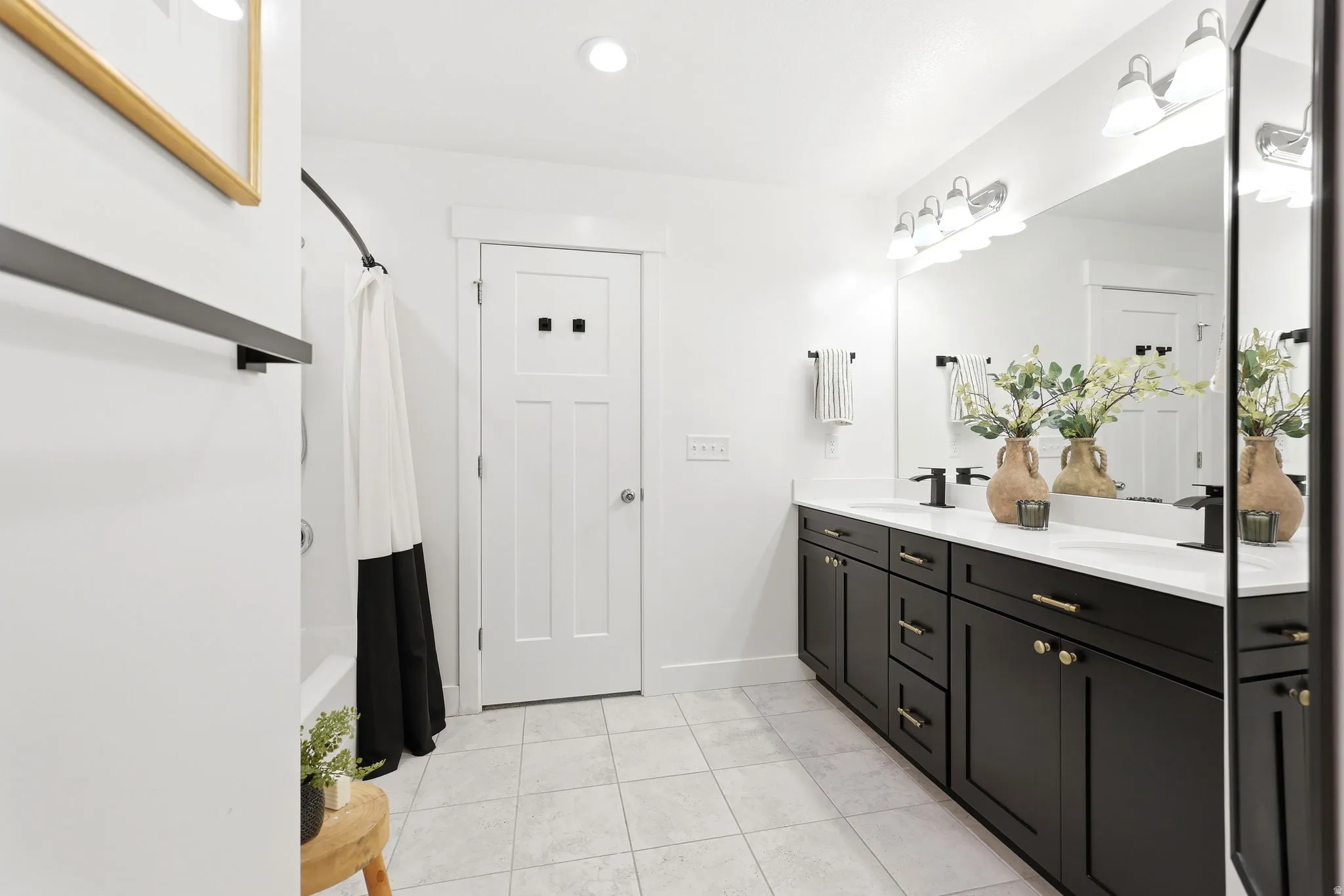Bathroom featuring a dual-sink vanity with black cabinetry, white countertops, and black hardware