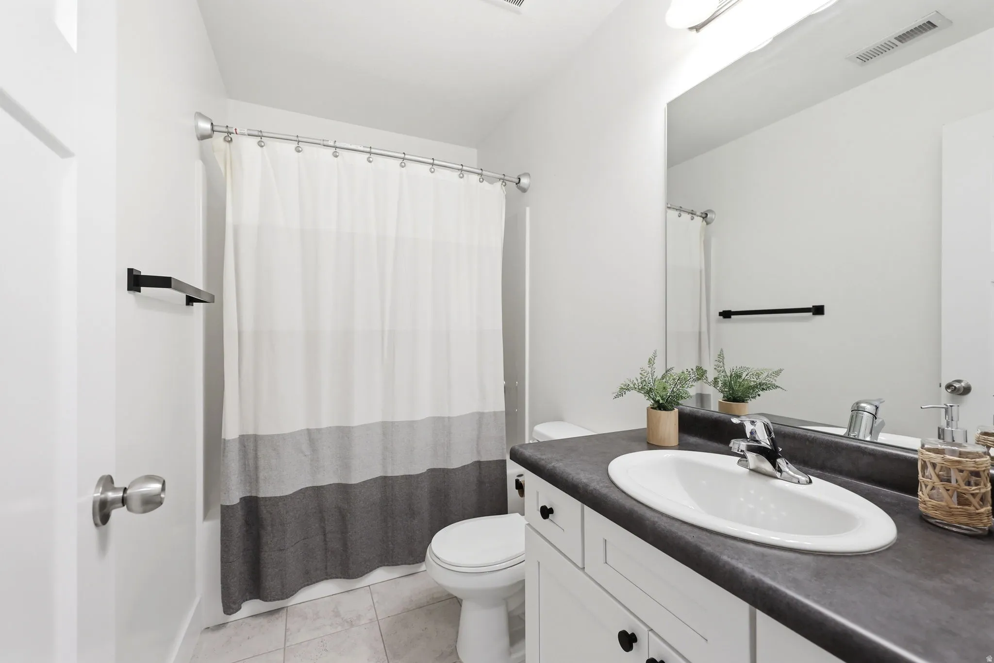 Bathroom featuring a white vanity with dark countertop, an integrated sink, and a chrome faucet