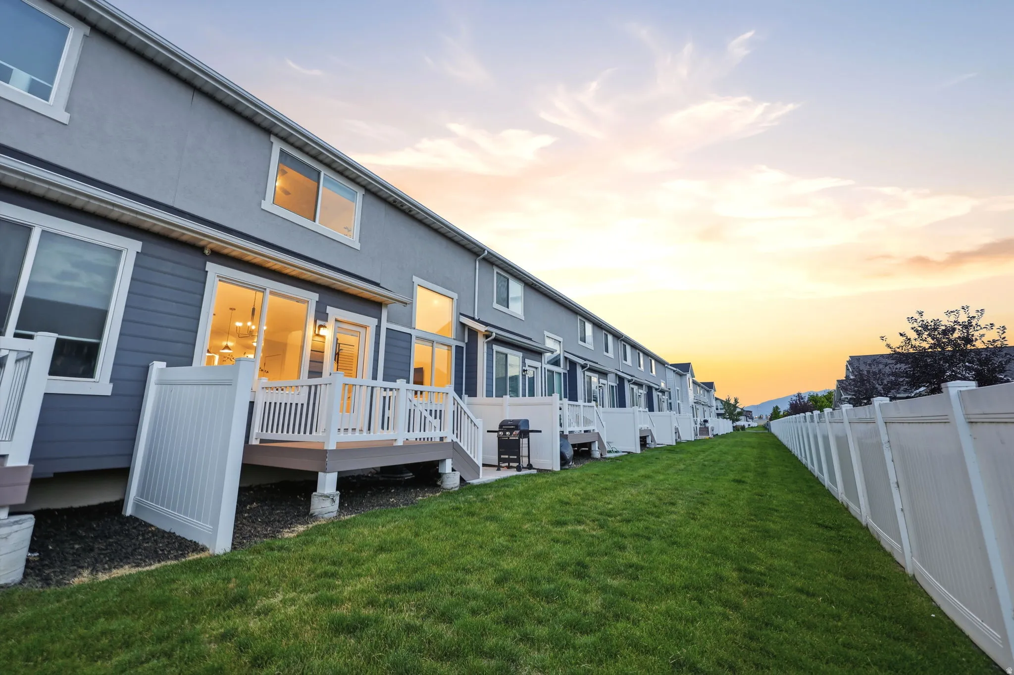 Rear exterior featuring a composite deck with white railings, a sliding glass door, and white frame windows