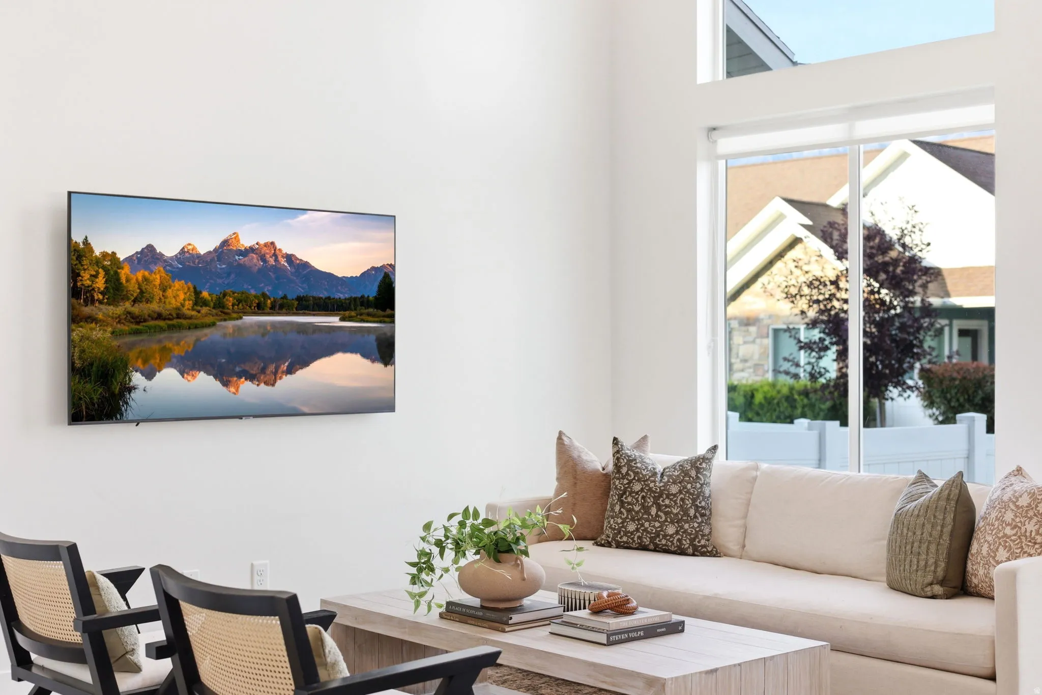 Bright living area featuring a large picture window with transom, a wall-mounted flat-screen display, and light-toned walls