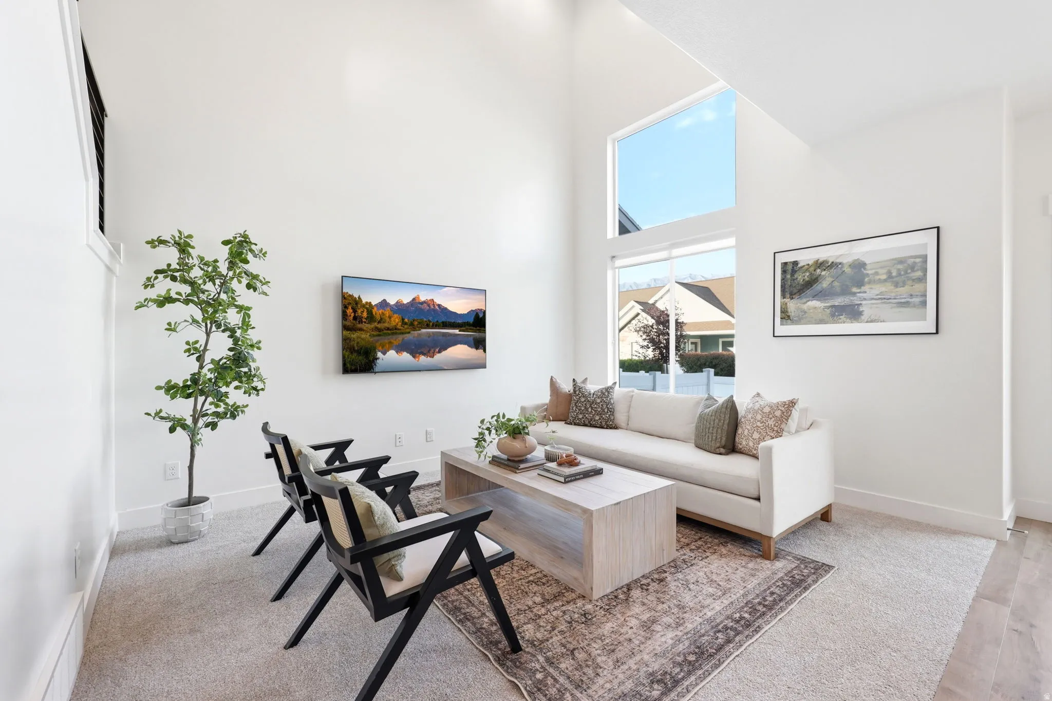 Vaulted ceiling living space featuring a large picture window, upper transom window, light-toned carpet, and wood-finish flooring