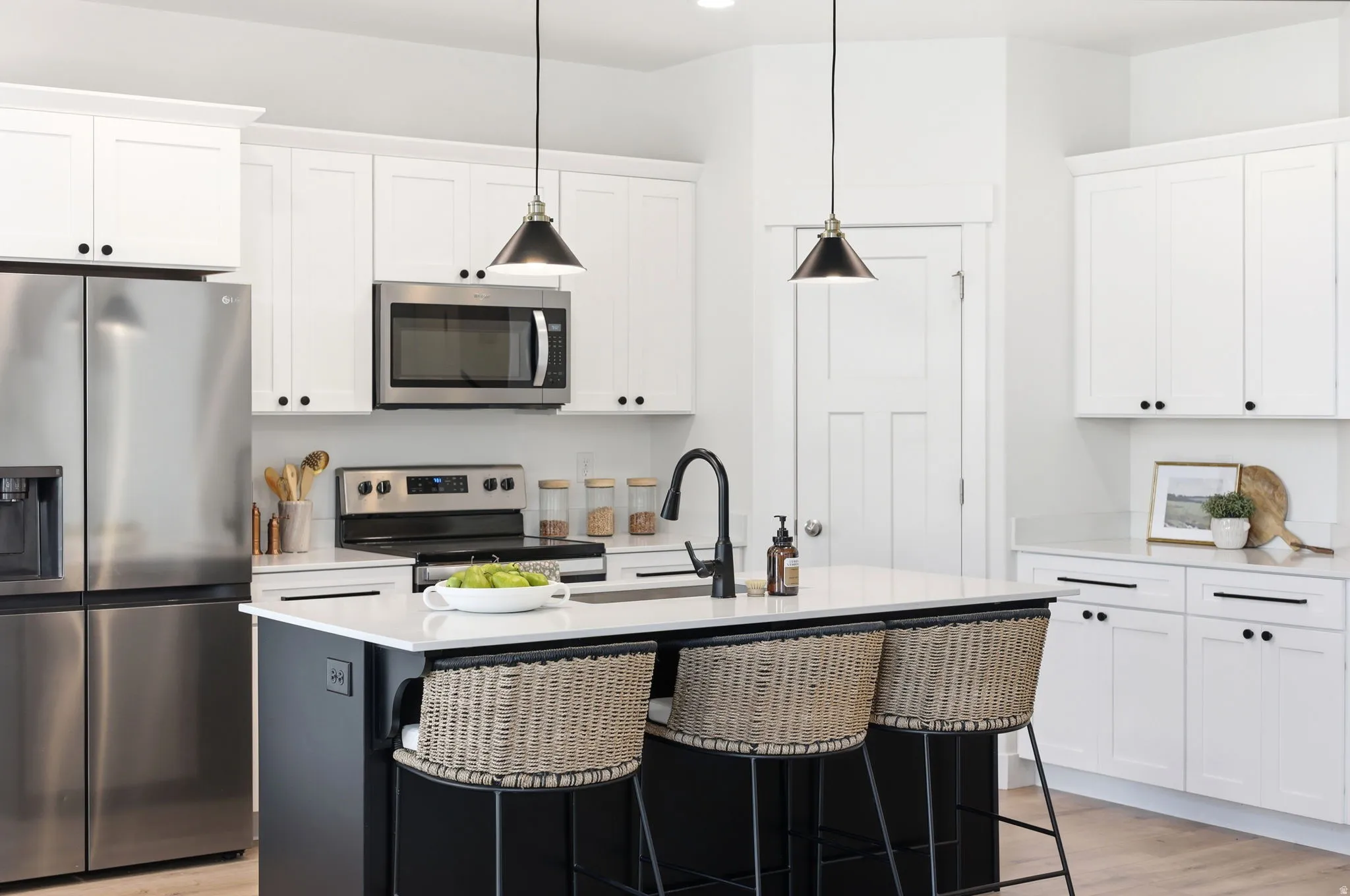 Contemporary kitchen featuring white shaker cabinetry and a contrasting black island