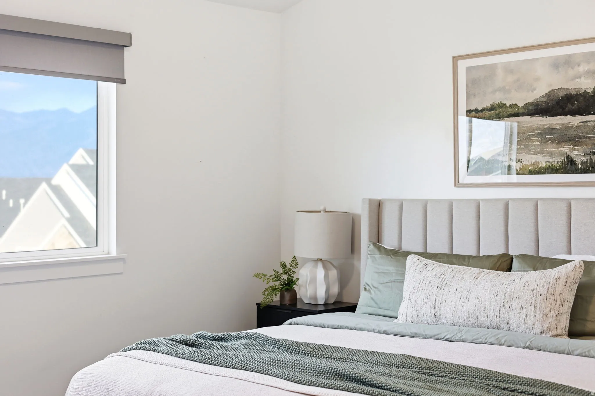 Bedroom featuring an upholstered headboard, a large window, and light-toned walls