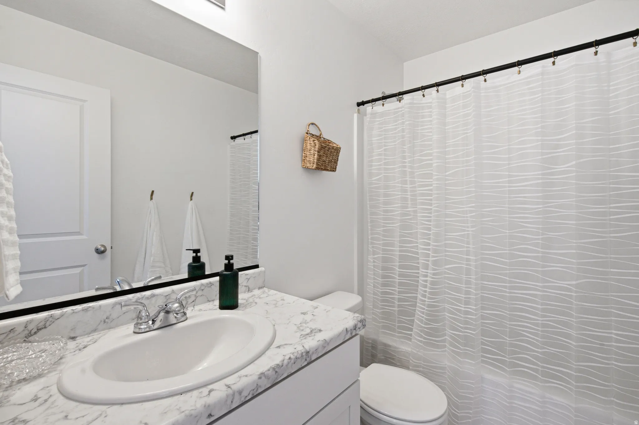 Bathroom featuring a white vanity with a patterned countertop, an oval undermount sink, and a chrome faucet