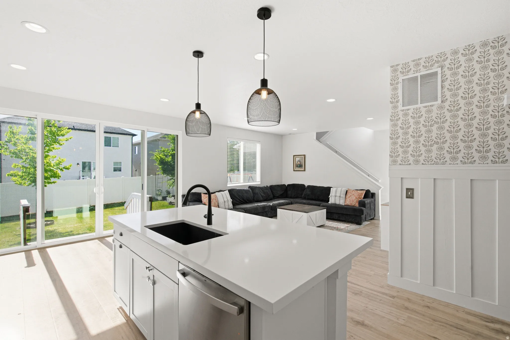 Kitchen island featuring a black sink and faucet, integrated dishwasher, and white countertop