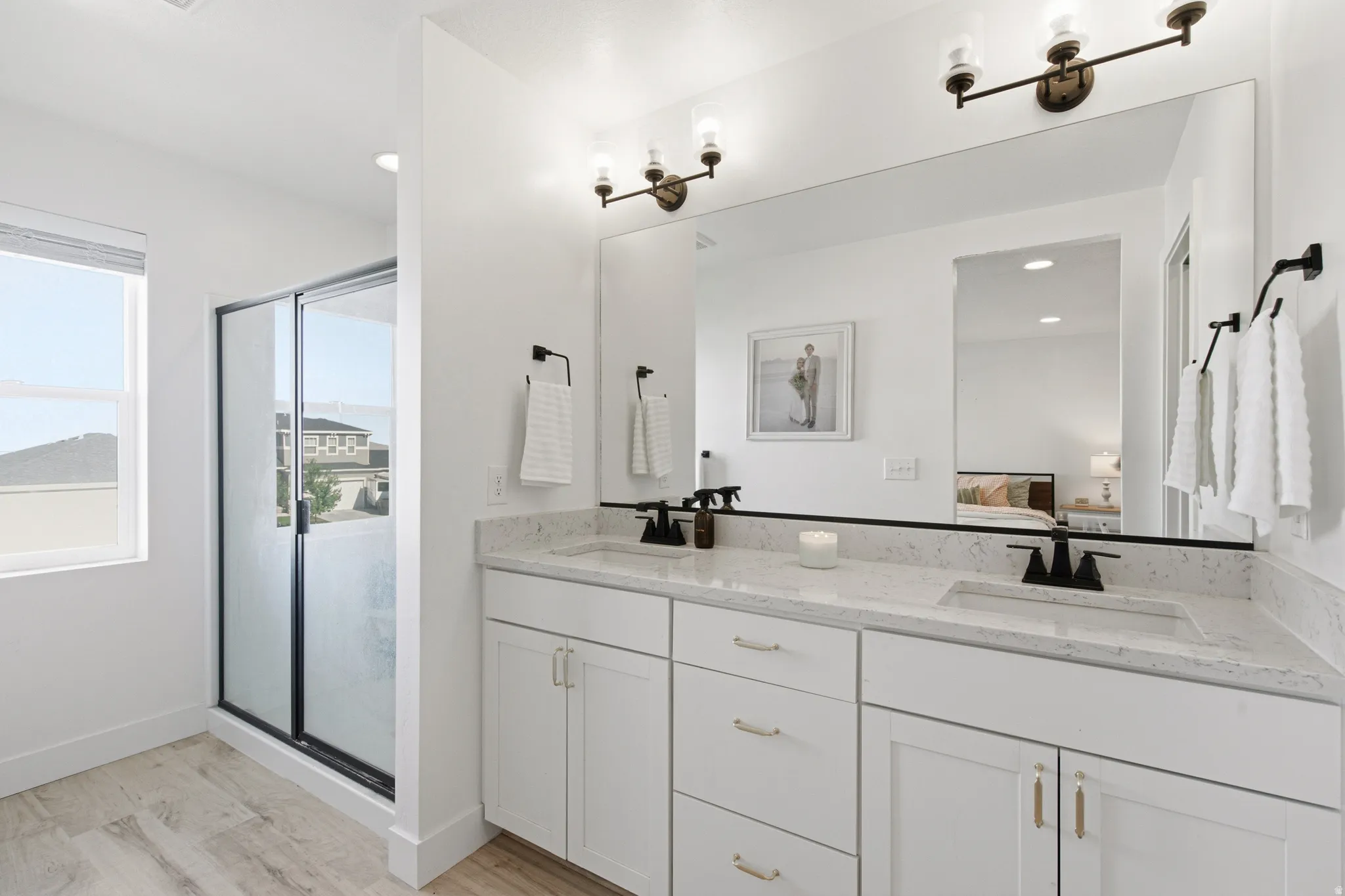 Dual vanity with light-toned countertop, integrated sinks, black hardware, and large mirror