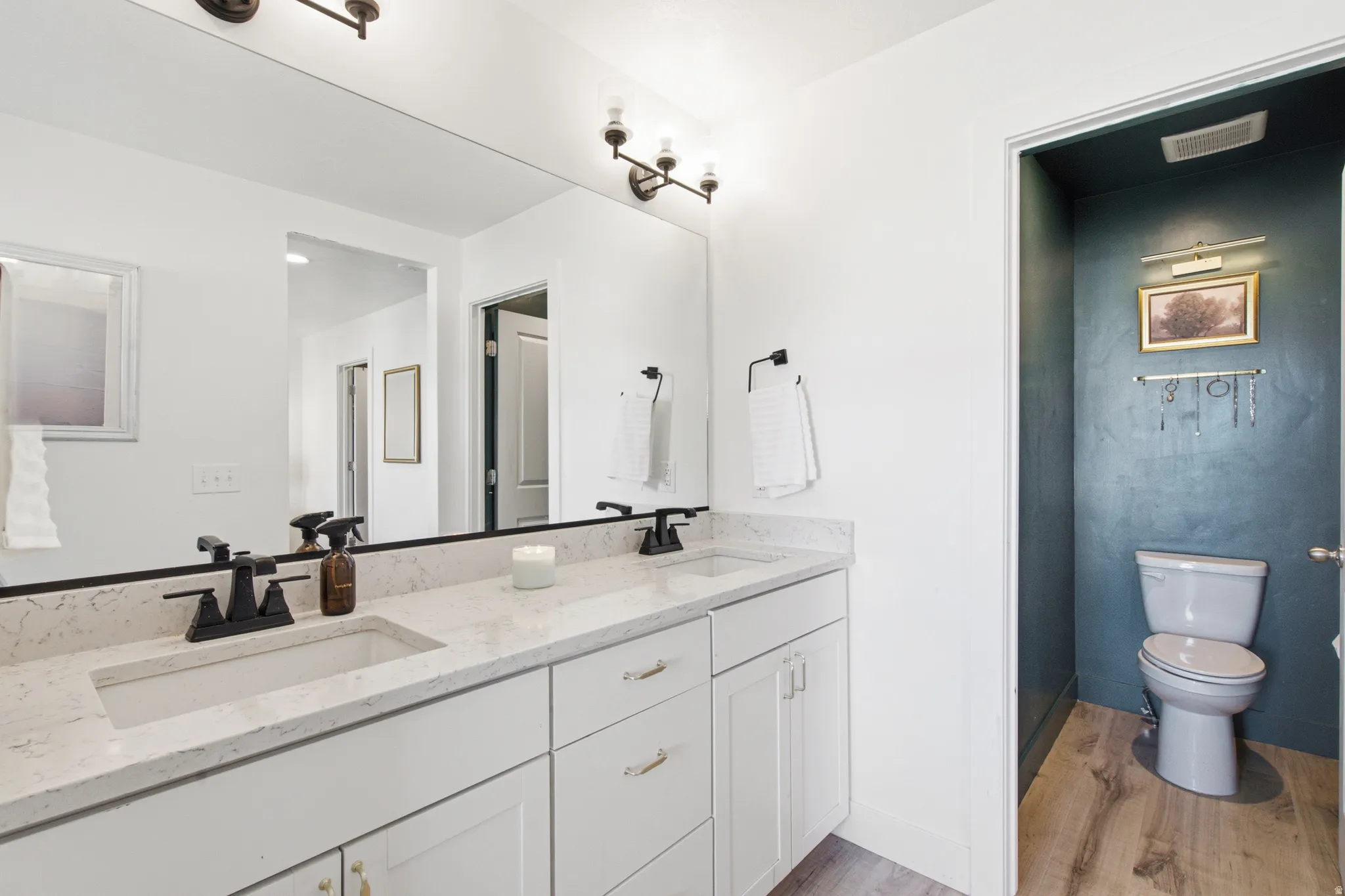 Double vanity featuring white cabinetry, light-toned countertops, and matte black fixtures