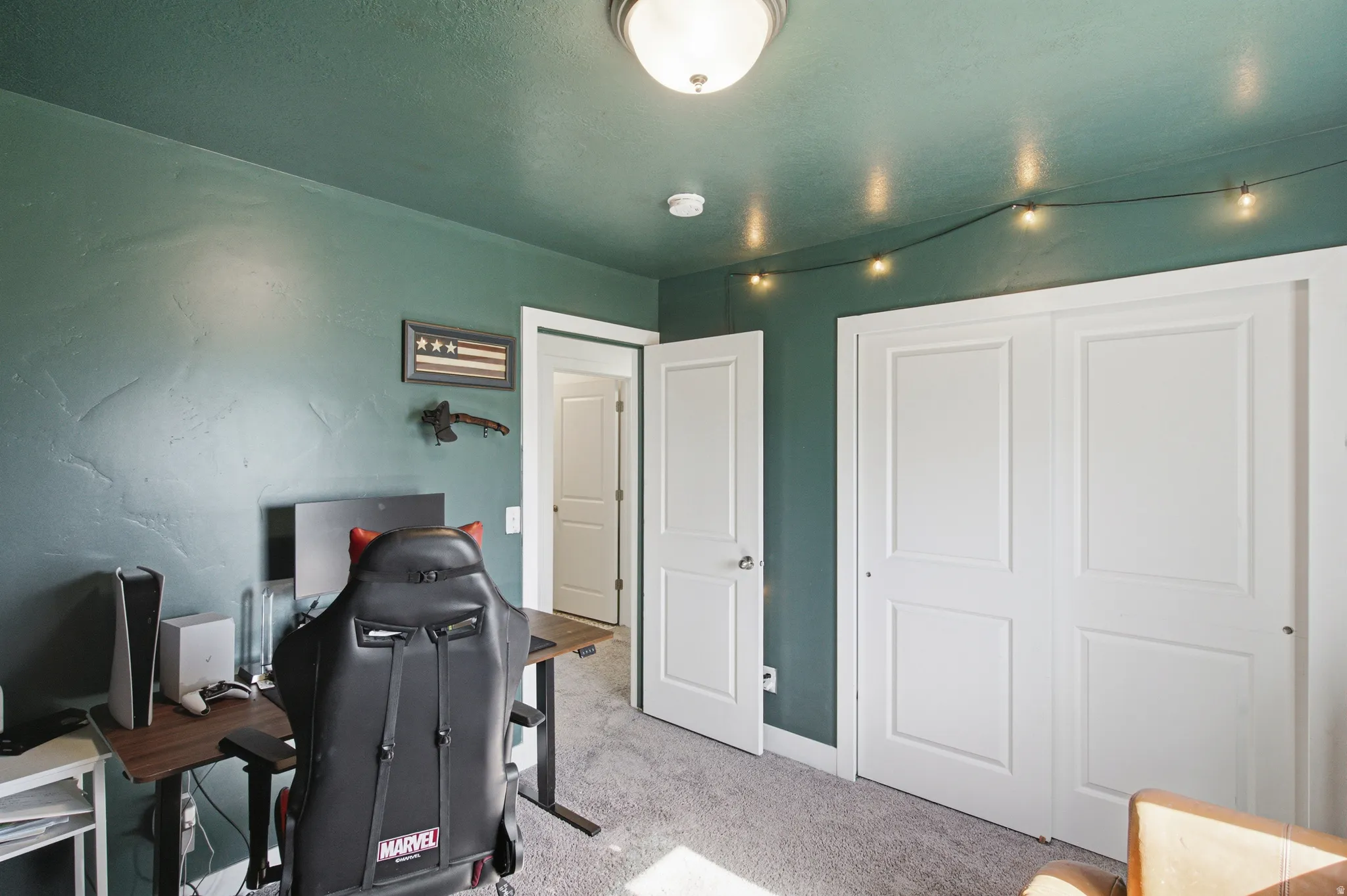 Carpeted room with deep green walls and ceiling, featuring white trim and white bi-fold closet doors