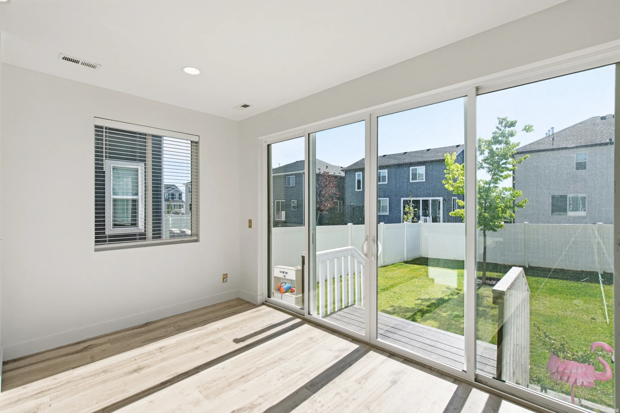Sliding glass doors provide access to an outdoor deck and fenced yard featuring a manicured lawn