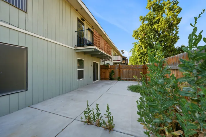 Rear patio area featuring a concrete slab, board-and-batten siding, and a wood privacy fence