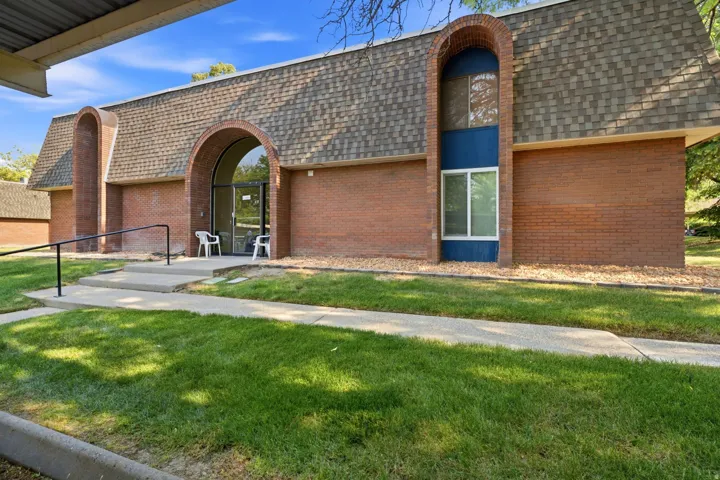 Brick facade featuring an arched entryway with glass doors and a shingled gambrel roof