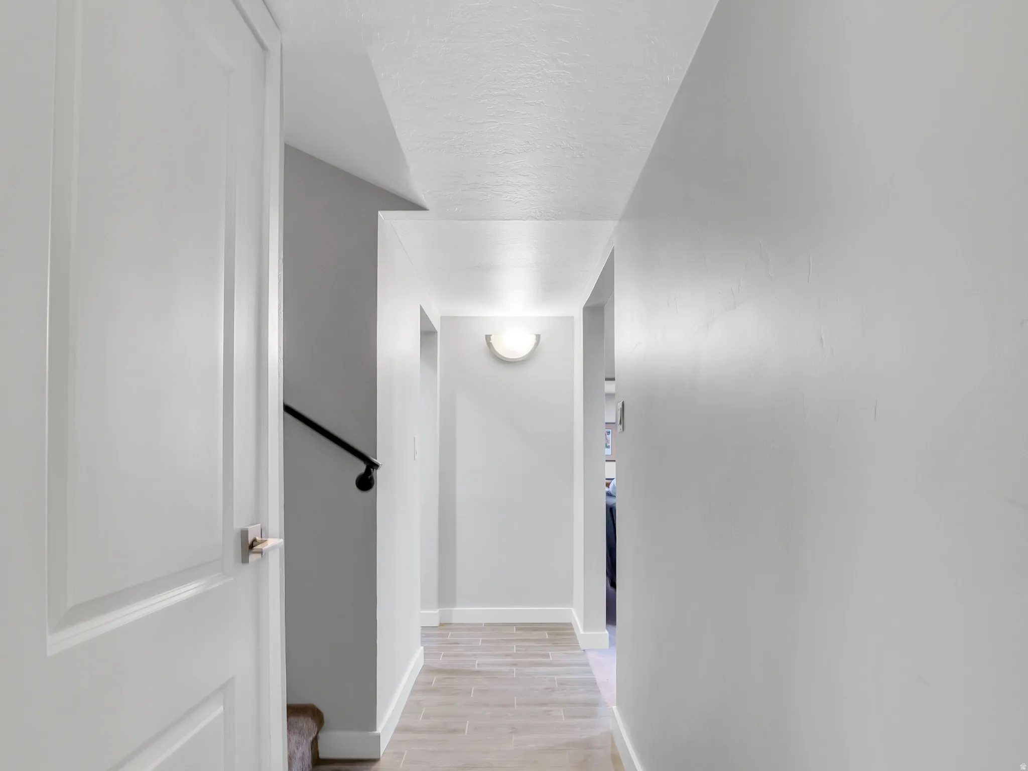 Hallway featuring wood-finish tile flooring, white baseboards, and neutral wall paint