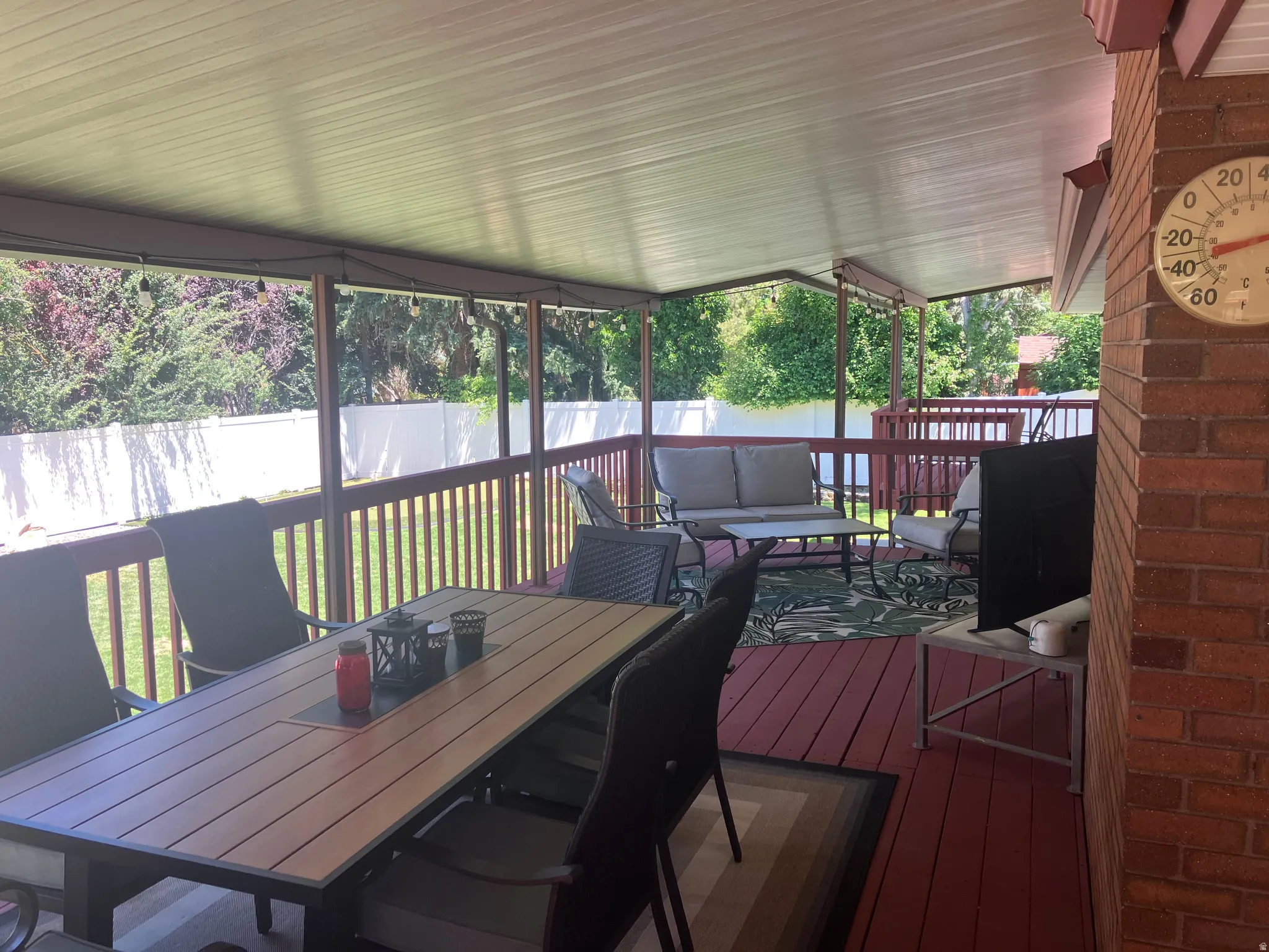 Covered outdoor deck with red-stained wood flooring and railing