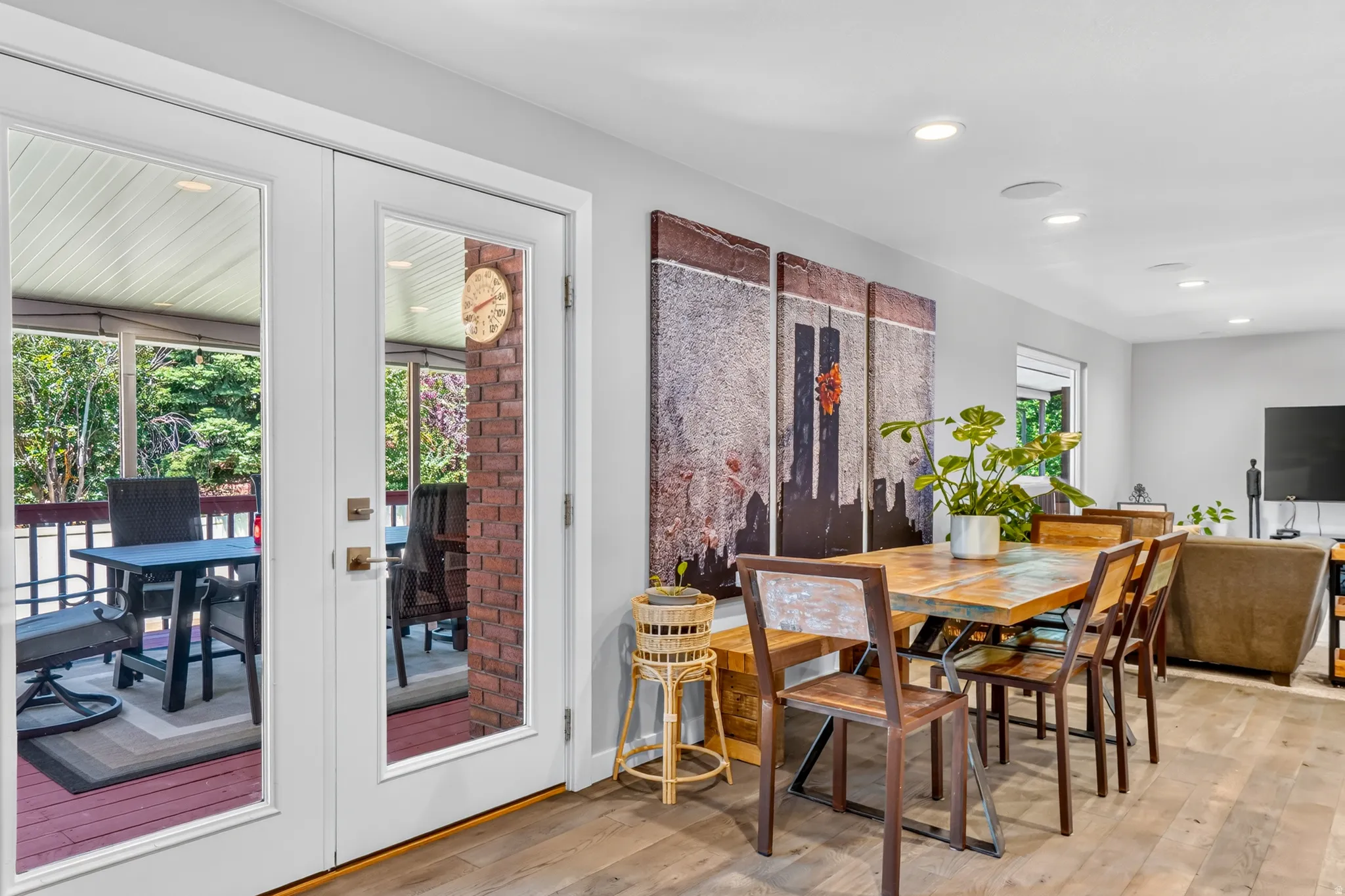 Dining area featuring wood-finish flooring, recessed lighting, and white French doors opening to an outdoor living space