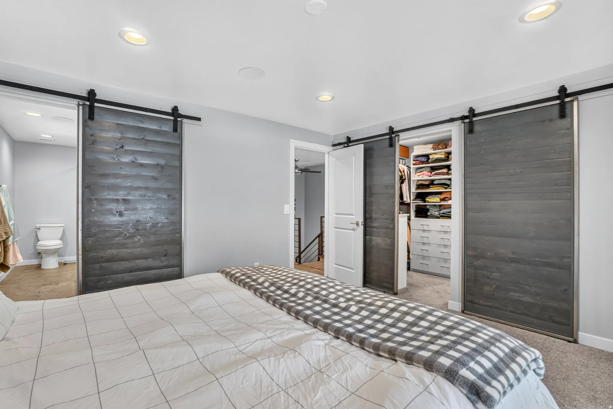 Bedroom featuring two sets of dark wood-finish sliding barn doors, recessed ceiling lighting, and light gray painted walls