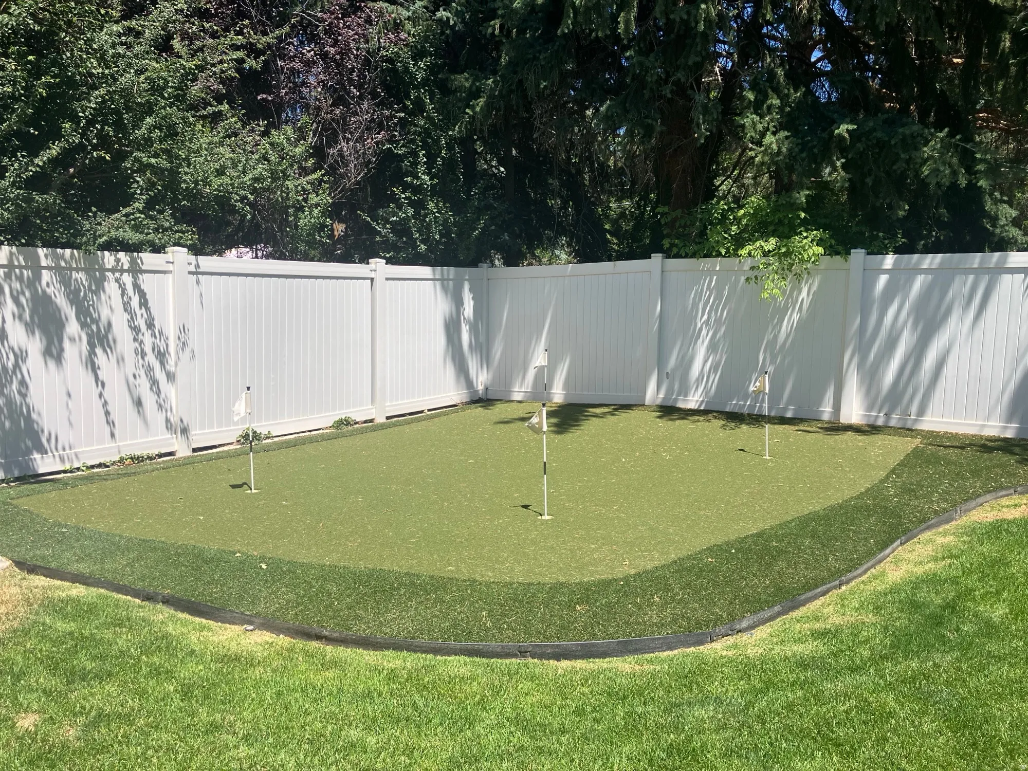 Outdoor putting green with synthetic turf and multiple cups