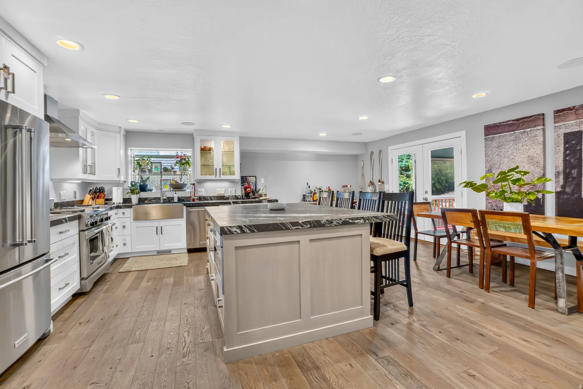 Kitchen featuring a central island with countertop seating, stainless steel appliances, wood-finish flooring, white cabinetry, and recessed lighting