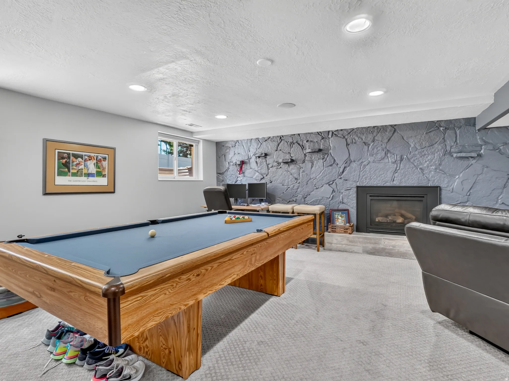 Recreation room with an accent wall featuring a stone-look finish surrounding a built-in fireplace