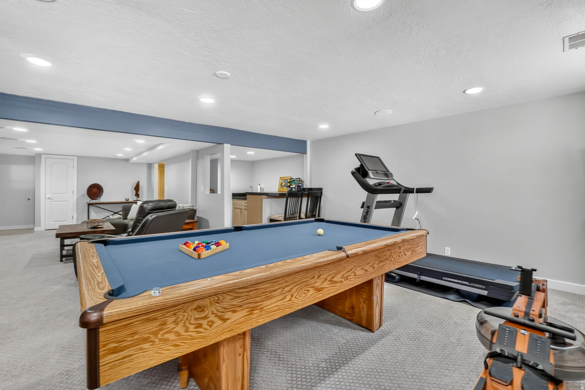 Spacious finished basement with recessed lighting, light gray walls, and gray carpeting throughout