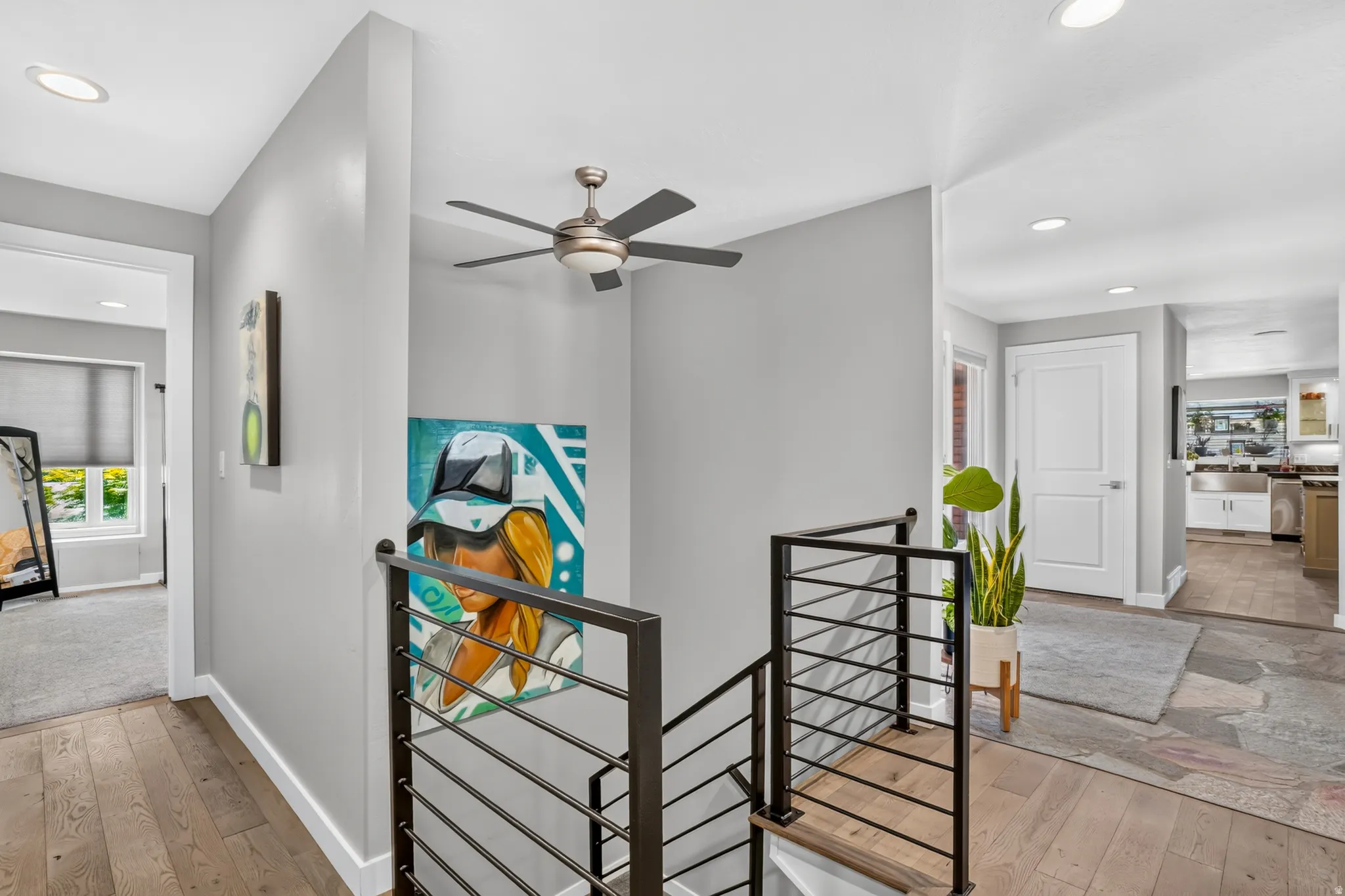 Interior hallway featuring wood-finish flooring and contemporary black metal stair railing