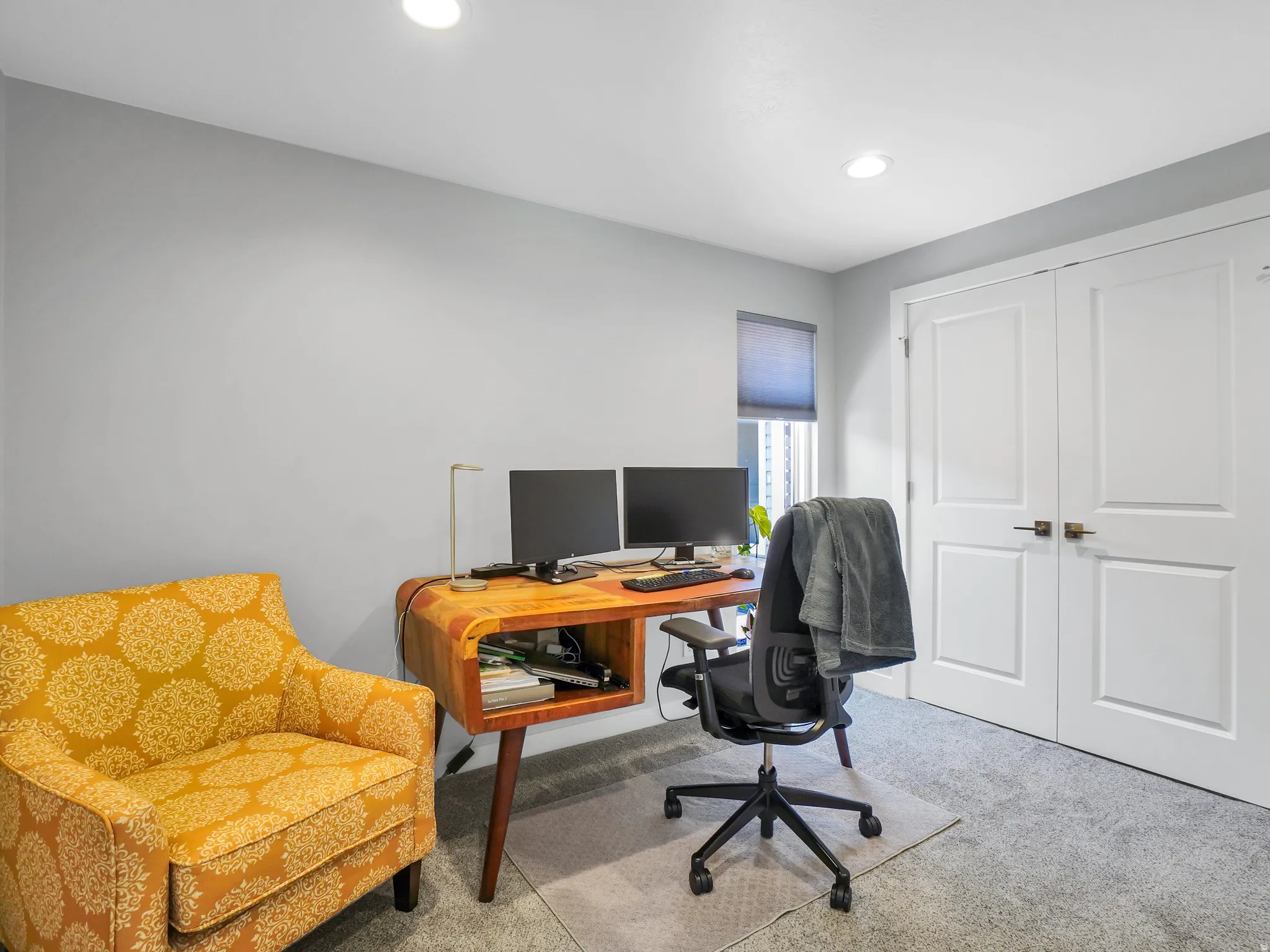 Recessed lighting illuminating a space with neutral gray walls and carpet flooring