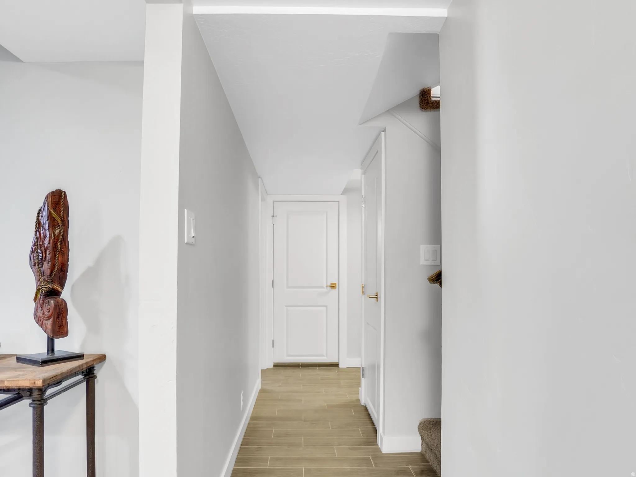 Hallway featuring wood-finish tile flooring, light gray wall paint, and white trim