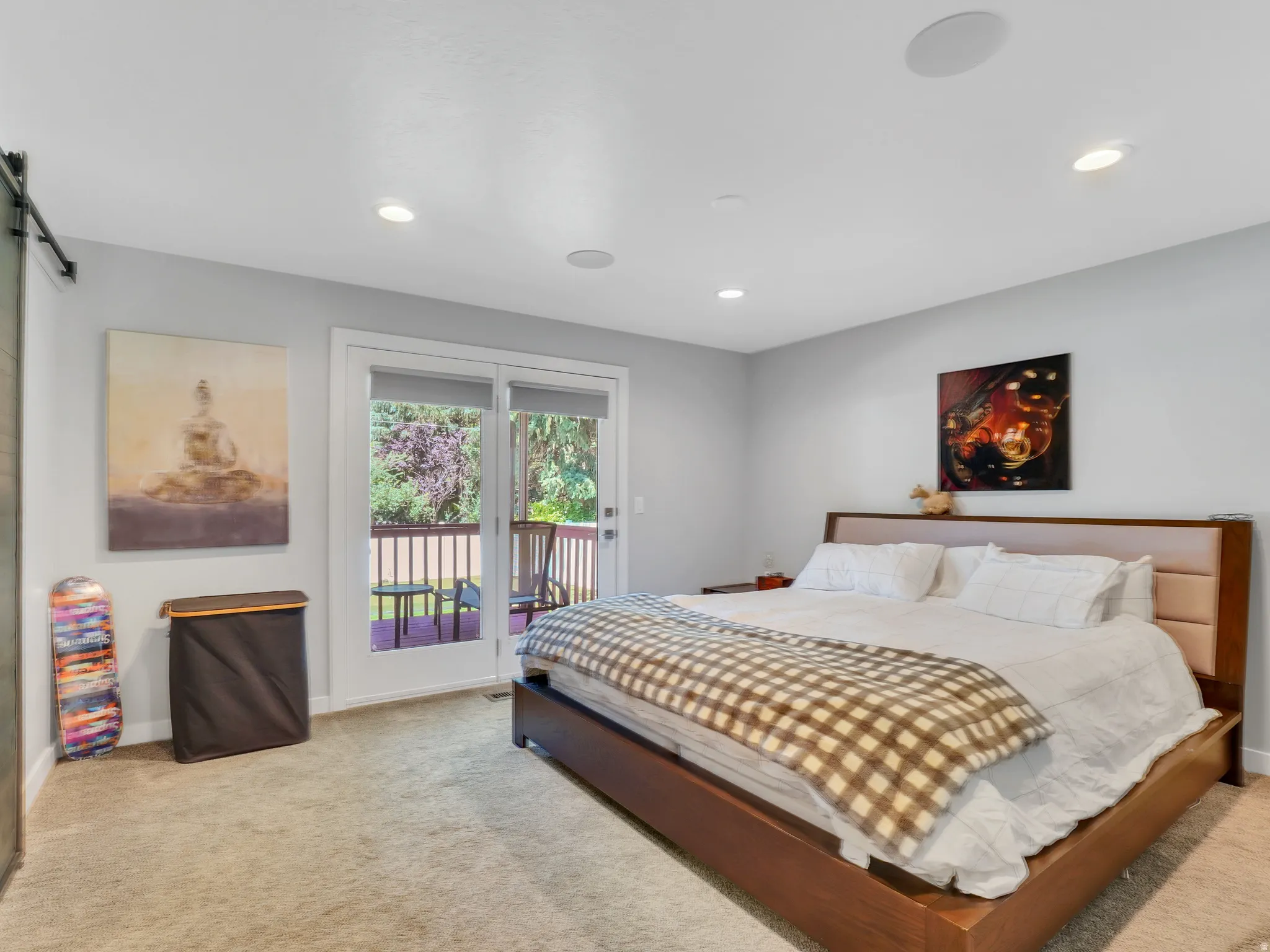 Room featuring a sliding barn door, recessed lighting, and a glass-paneled French door opening to a deck