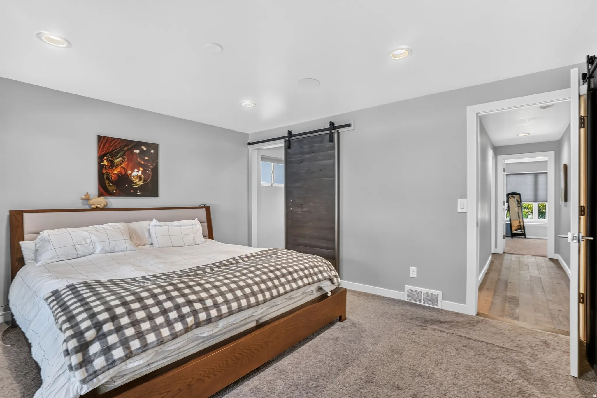 Bedroom featuring recessed lighting, a dark wood-finish barn door, and light gray wall paint