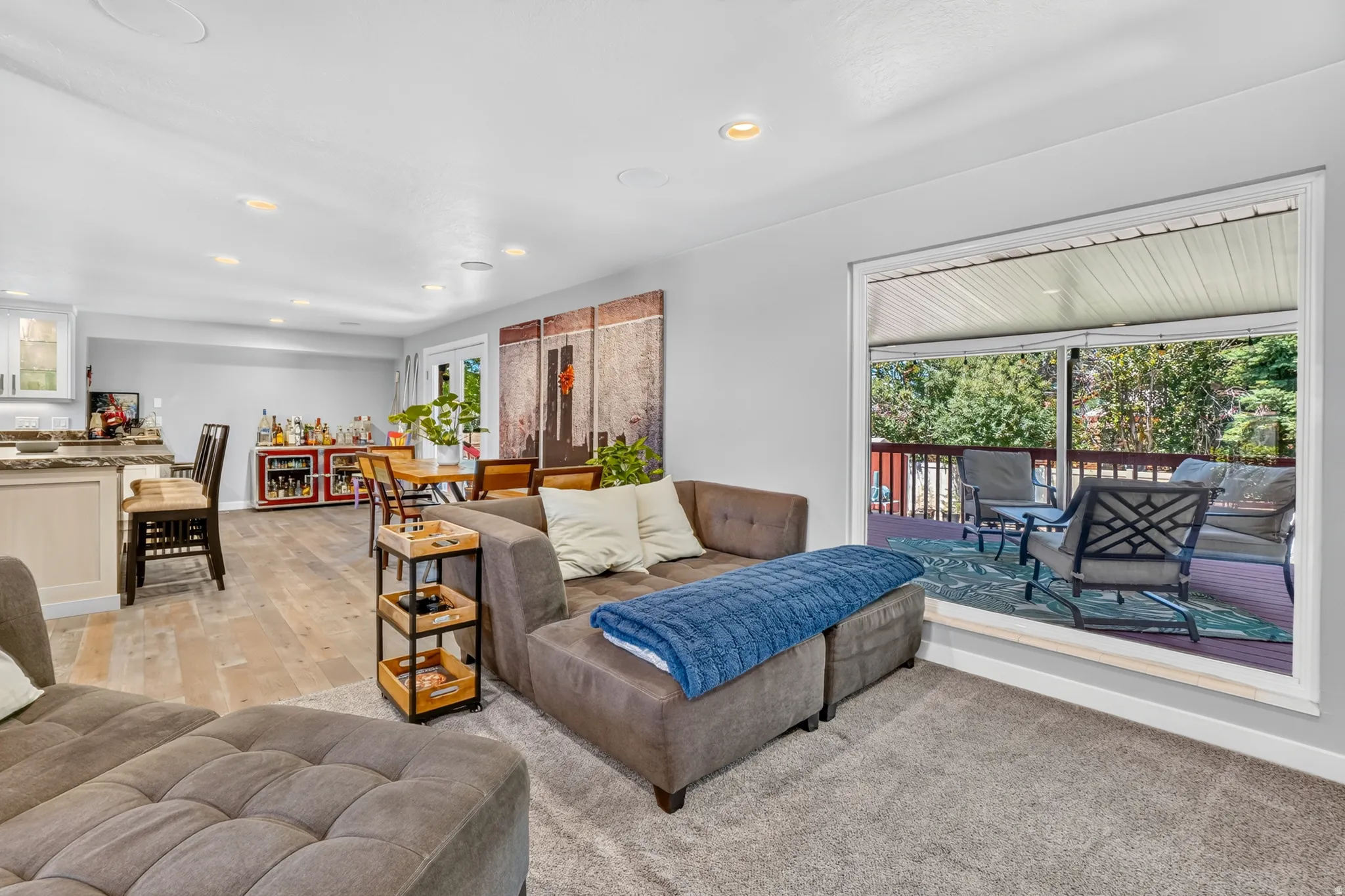 Carpeted living area with a large sliding glass door opening to a covered outdoor deck