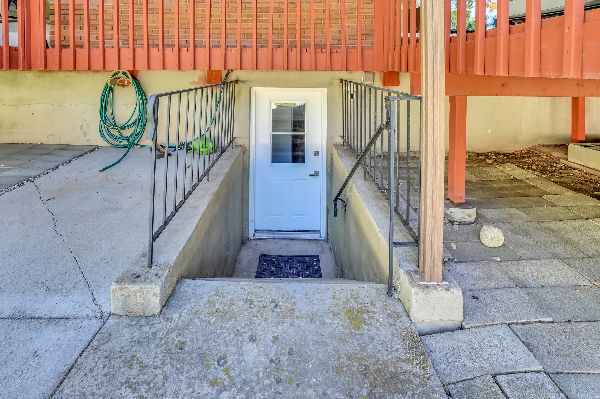 Lower level entry with a white paneled door, complemented by black iron railings and concrete steps