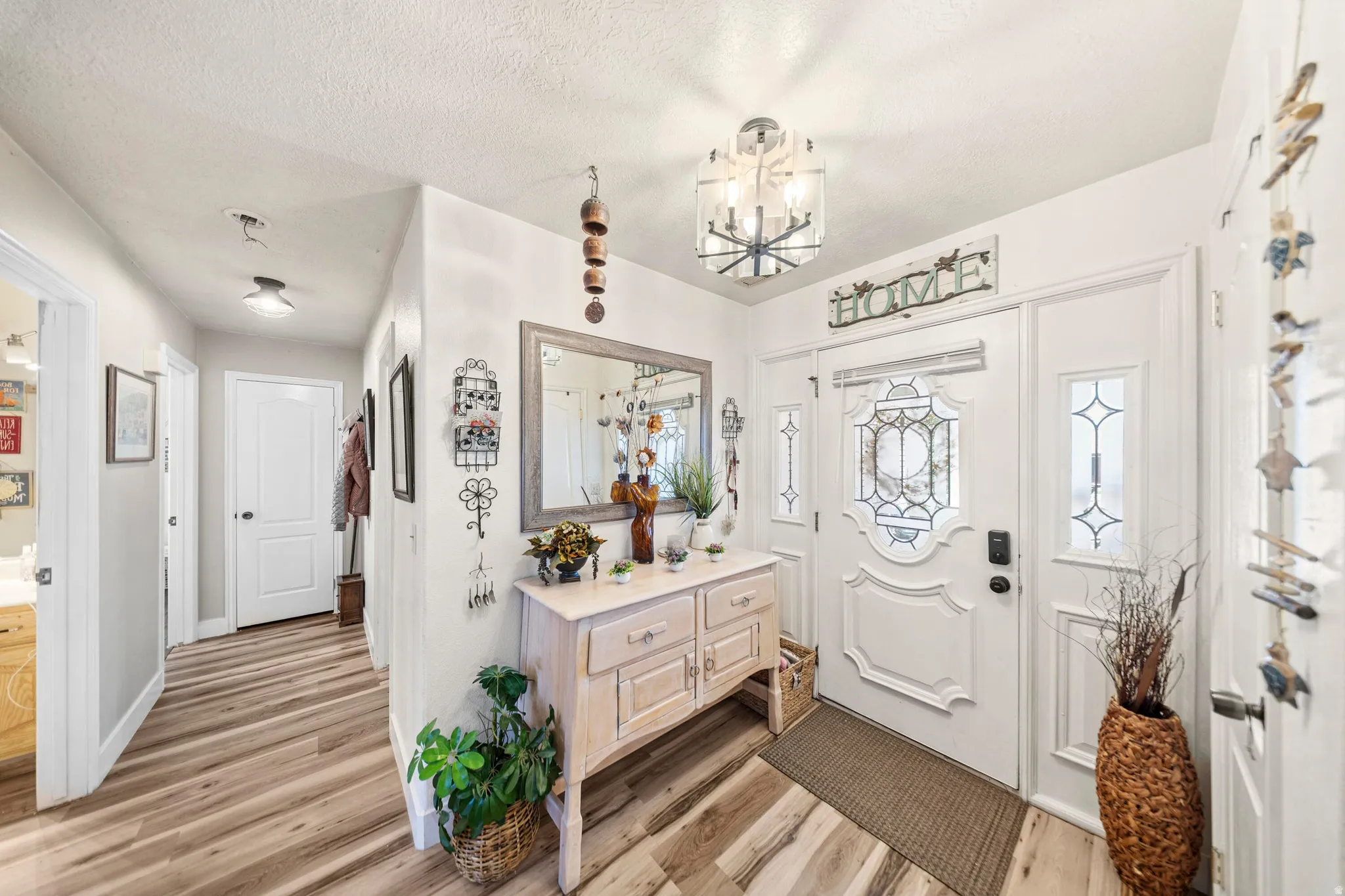 Entryway featuring a decorative front door with side light panels, wood-finish flooring, and a modern ceiling light fixture