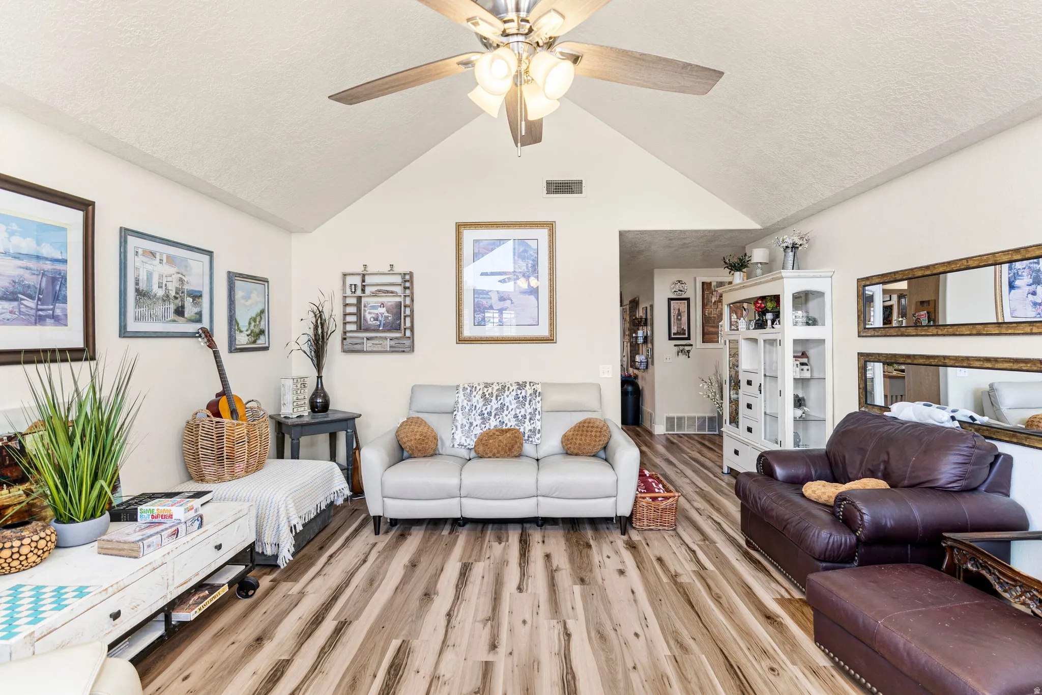 Living area featuring wood-finish flooring, a vaulted ceiling, and a ceiling fan with integrated lighting