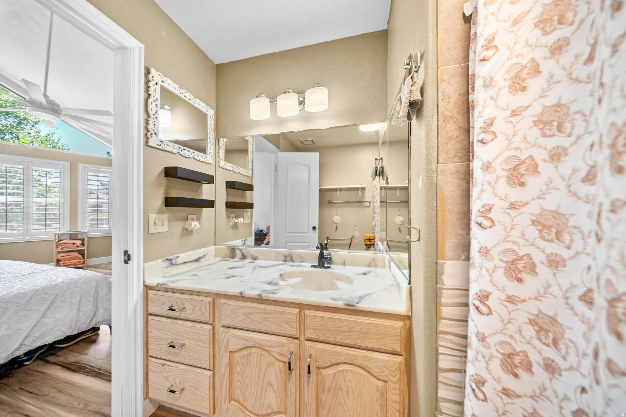 Bathroom vanity featuring a light-colored wood cabinet, white countertop with gray veining, and a polished chrome faucet