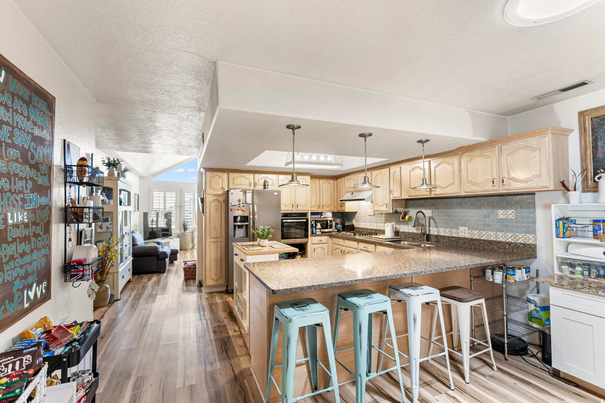 Kitchen featuring a large central island with seating, ample cabinetry, stainless steel appliances, a tiled backsplash, and wood-finish flooring