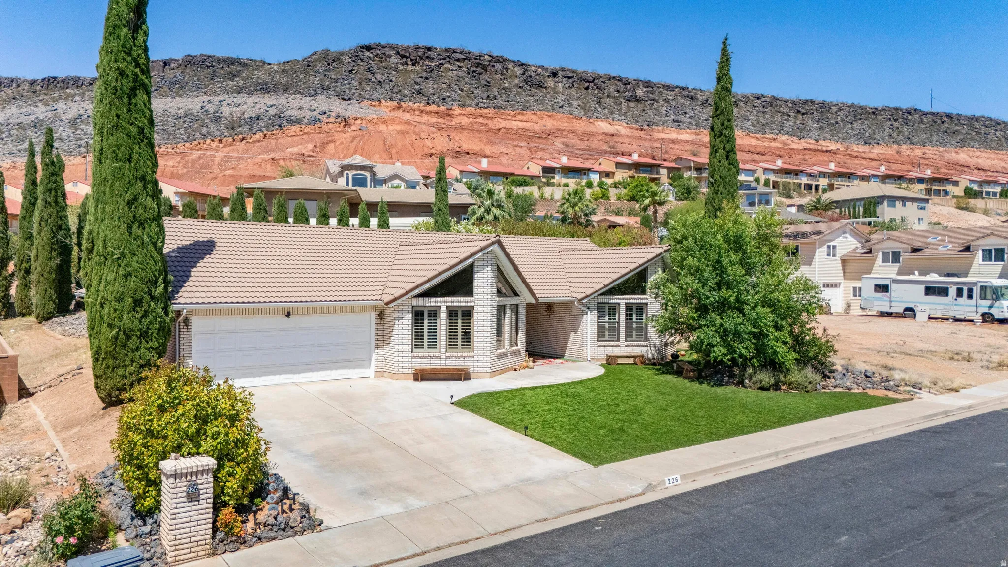 Single-story residence featuring a two-car garage, light-colored tile roofing, and a stone facade