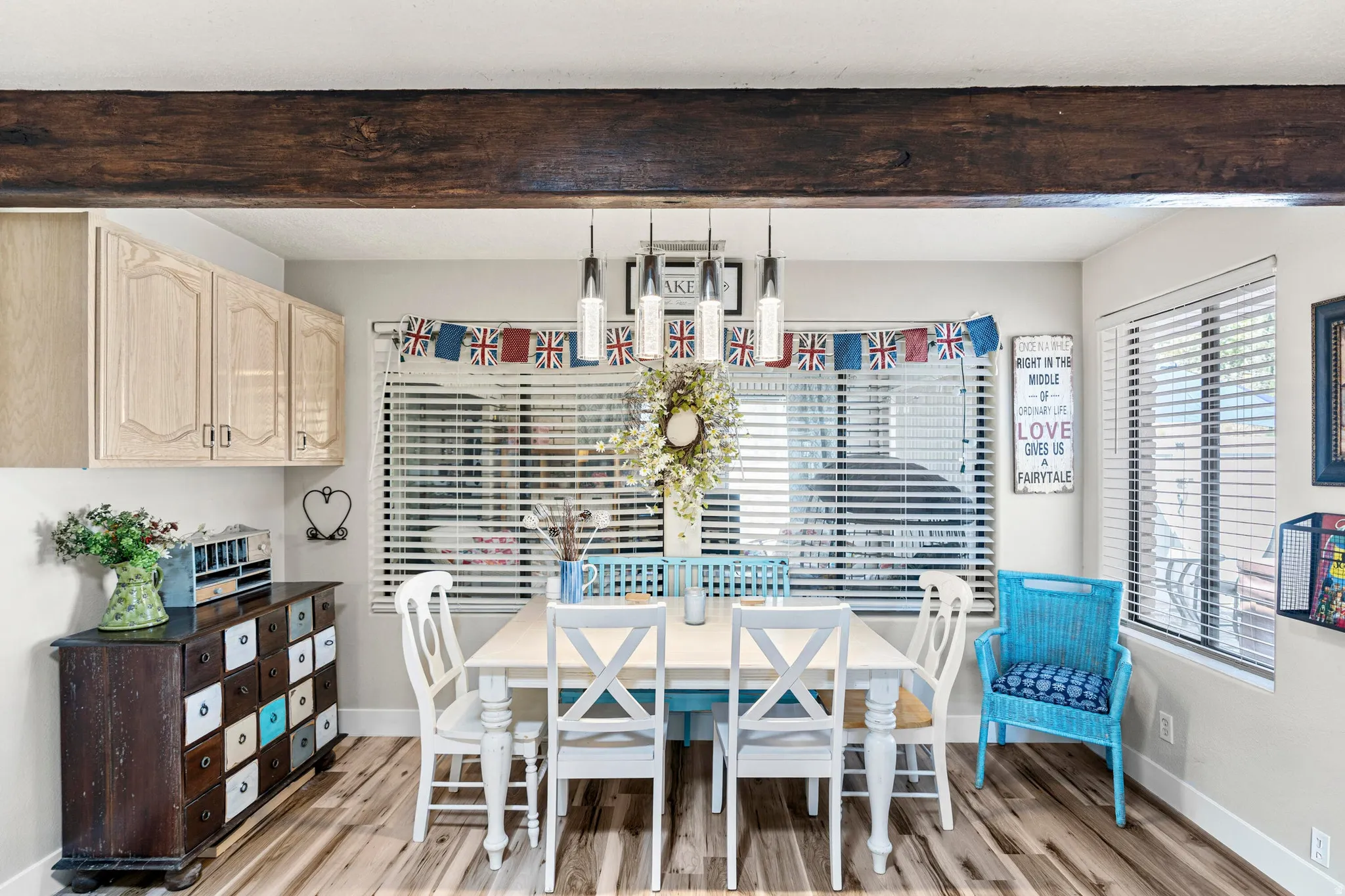 Dining area featuring wood-finish flooring, a rustic wood beam, and two large windows with blinds