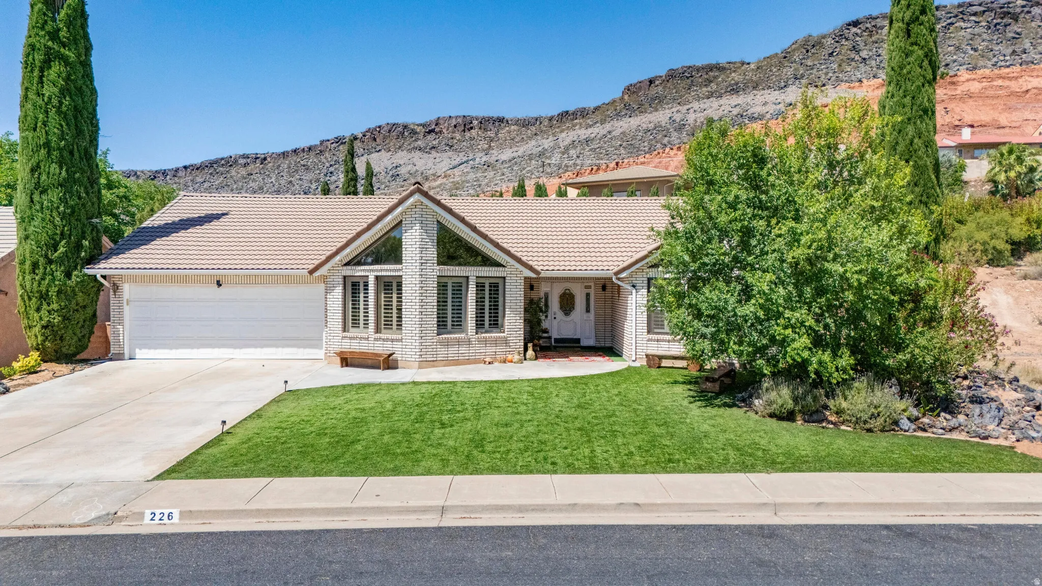 Single-story residence featuring a two-car garage, front lawn, and paved driveway