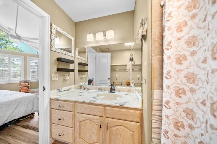 Bathroom vanity featuring a light-colored wood cabinet, white countertop with gray veining, and a polished chrome faucet