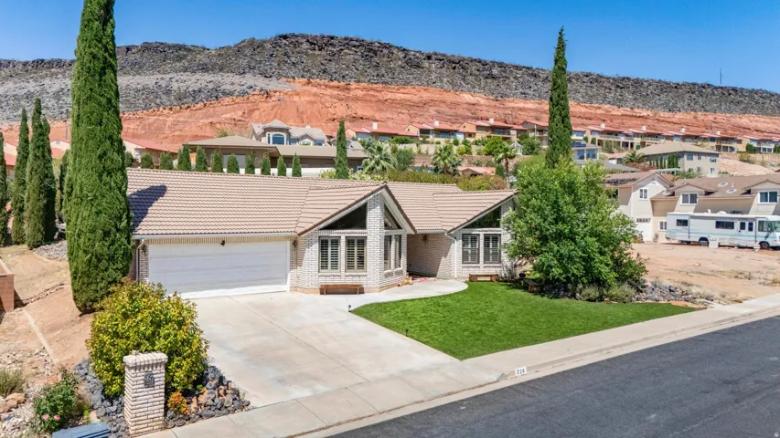 Single-story residence featuring a two-car garage, light-colored tile roofing, and a stone facade