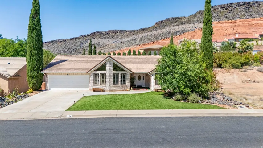 Tan tile roof residential architecture with a two-car garage, front lawn, and a light-colored stucco exterior
