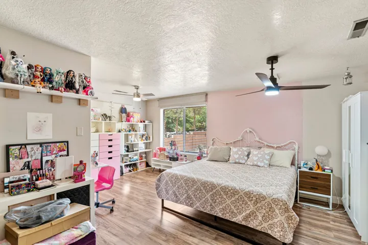 Bedroom featuring wood-finish flooring, a contemporary ceiling fan, and a window with horizontal blinds