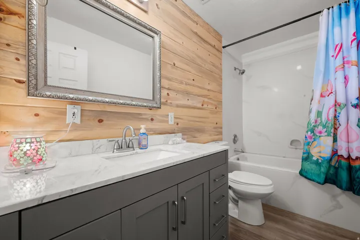 Bathroom vanity featuring a grey base cabinet, white countertop, and a chrome faucet set against a horizontal wood-finish accent wall