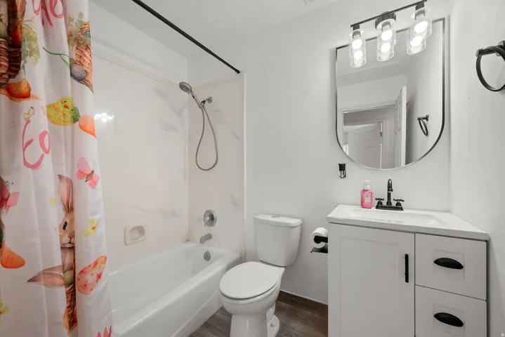 White vanity with a single basin sink, matte black faucet, and a contemporary arched mirror