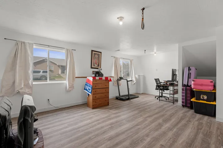Open concept room featuring two windows, wood-finish flooring, white walls, and a visible stairwell opening
