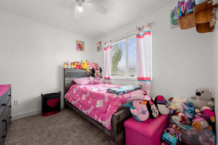 Bedroom featuring a window with blinds, carpet flooring, and a ceiling fan with integrated lighting