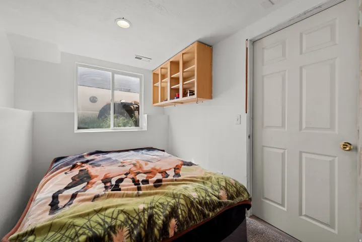 Recessed lighting illuminating a white-painted room with a window, wood-finish shelving, and a paneled door with brass hardware