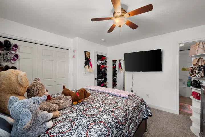 Bedroom featuring plush carpeting, a ceiling fan with integrated lighting, and white bi-fold closet doors